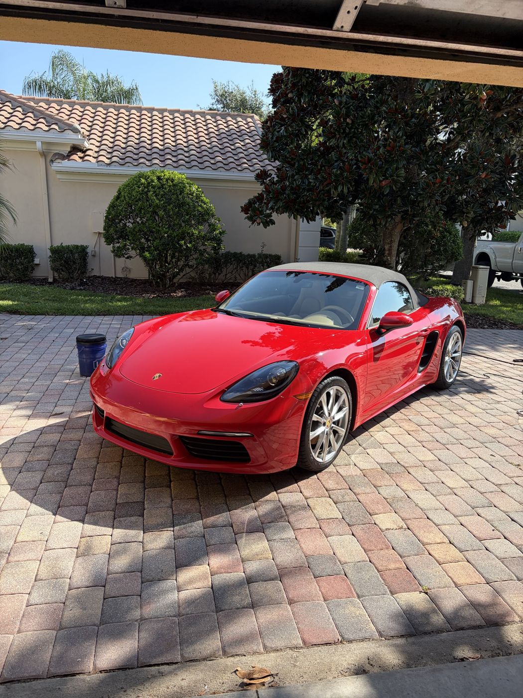 Red Porsche 718 Boxster convertible gleaming on a paver driveway